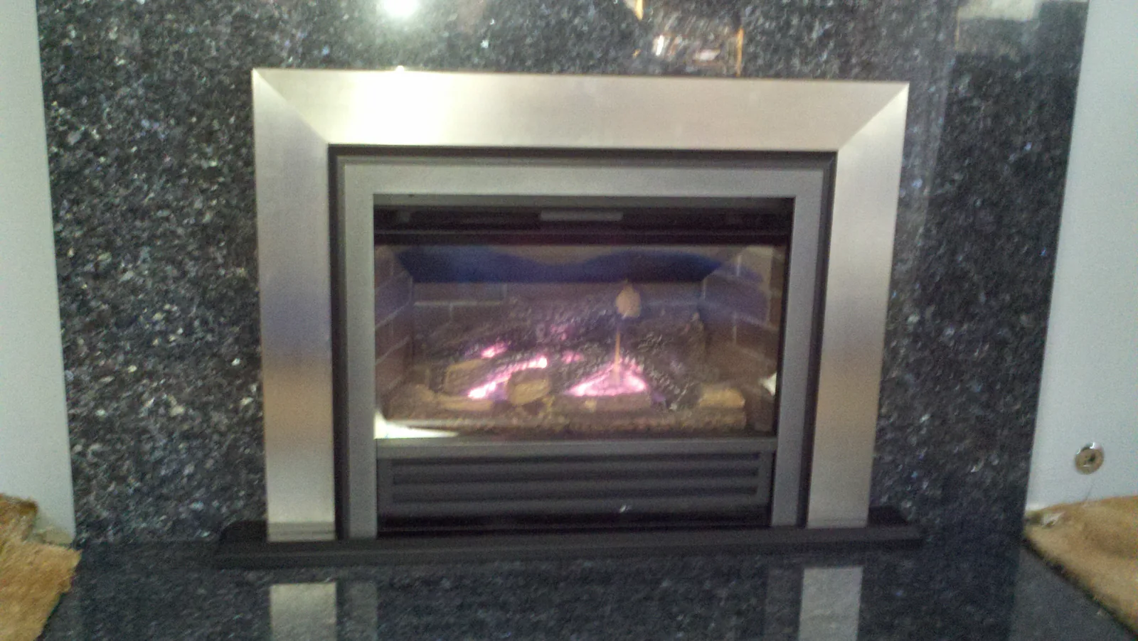 Gas fireplace with stainless surround and dark stone finish Gas fireplace with stainless surround and dark stone finish